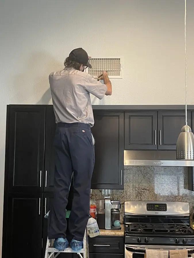 Technician inspecting an air vent during HVAC service in Capitola
